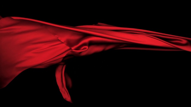 红色丝质织物在超慢的动作中横向流动和摆动，近景，黑色背景视频素材