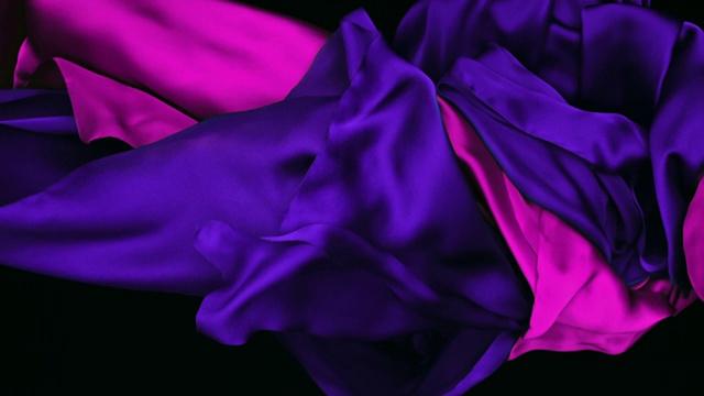 蓝色和粉色的丝质织物在超慢的动作中横向流动和波动，近景，黑色背景视频下载