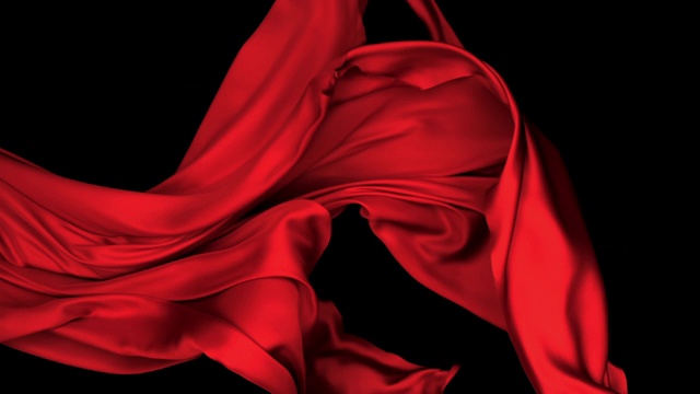 红色丝质织物在超慢的动作中横向流动和摆动，近景，黑色背景视频素材