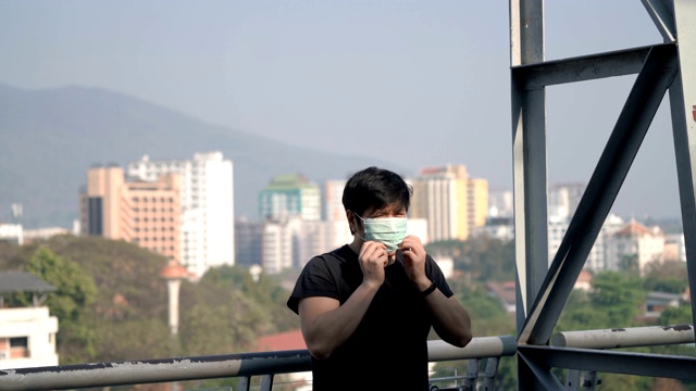 戴着空气污染口罩在屋顶上的城市背景视频素材