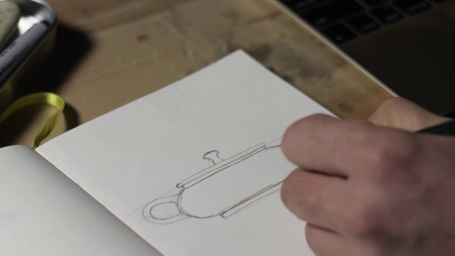 一个男性的手在纸上画一个陶壶素描特写。男性的手用铅笔画画。宏观的观点。4 k的视频。59.94帧/秒视频下载