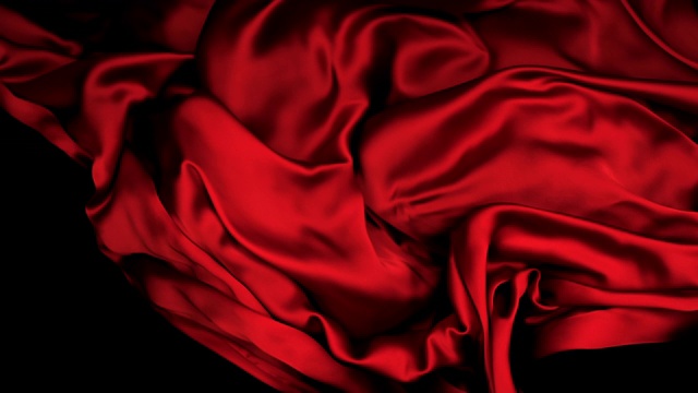 深红色丝质织物在超慢的动作中横向流动和摆动，近景，黑色背景视频素材