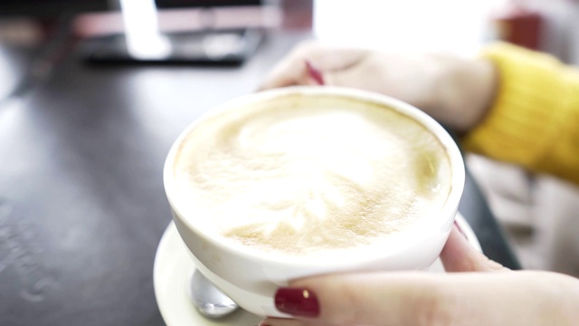 一个漂亮的女人在咖啡店喝咖啡吃牛角面包视频素材