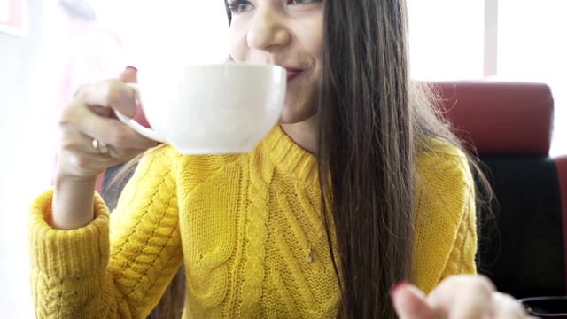 一个漂亮的女人在咖啡店喝咖啡吃牛角面包视频素材