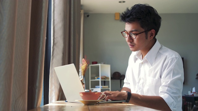 年轻的亚洲商人在咖啡馆里用笔记本电脑工作视频素材