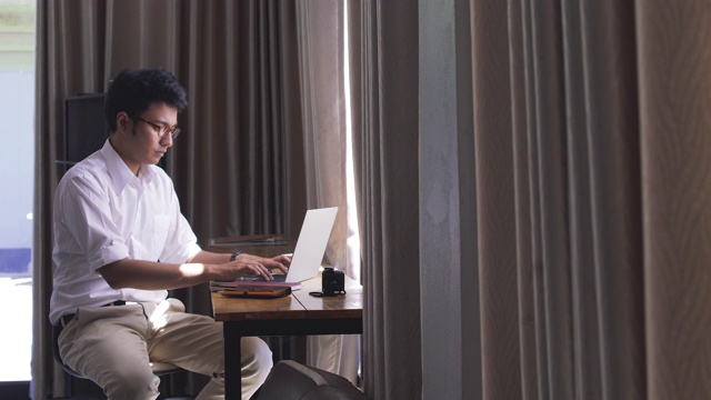 年轻的亚洲商人在咖啡馆里用笔记本电脑工作视频素材
