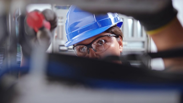一名女电工的脸，正在看电气面板和连接电线视频素材