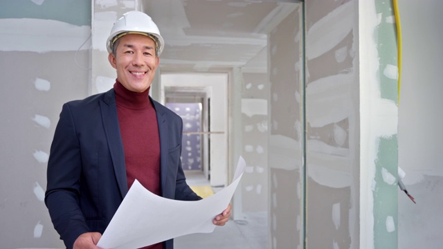一位微笑的男建筑师看着建筑内部的平面图的肖像视频素材