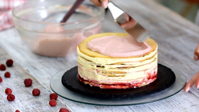 糕点师用糕点抹刀在蛋糕上涂上粉色奶油。视频下载