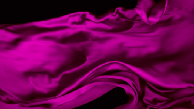 粉色丝质织物在超慢的动作中横向流动和摆动，近距离，黑色背景视频素材