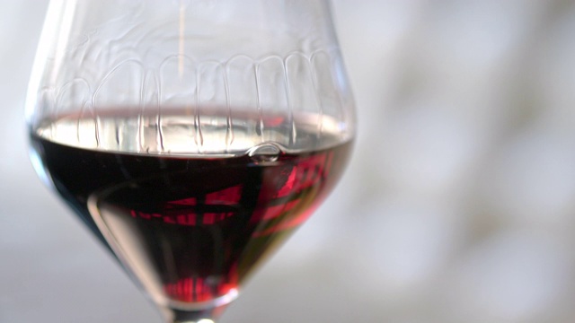 红酒在斟满后在玻璃杯中移动并放置在桌子上。视频素材