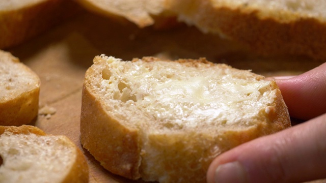 木板上的新鲜面包上涂着黄油。视频下载
