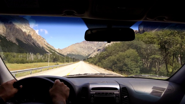 驱动板。汽车在一个乡村道路，山脉，山谷- POV -观点前-挡风玻璃，仪表盘，手，方向盘参考。的一天。视频素材