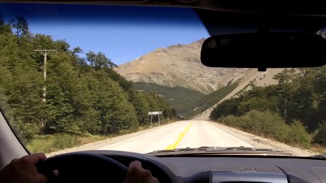 驱动板。汽车在一个乡村道路，山脉，山谷- POV -观点前-挡风玻璃，仪表盘，手，方向盘参考。的一天。视频素材
