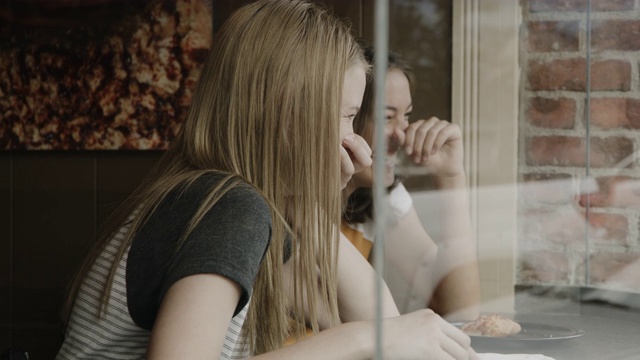 近距离拍摄的女孩坐在披萨店的窗口边说说笑笑/普罗沃，犹他州，美国视频素材