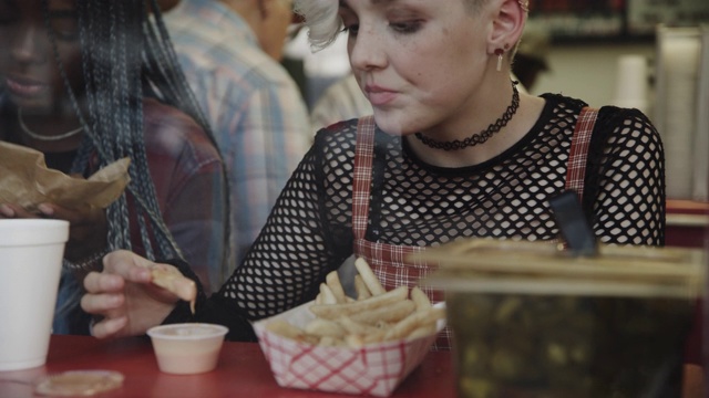 美国犹他州普罗沃，一个女孩在咖啡馆的橱窗里蘸着酱汁吃薯条视频素材