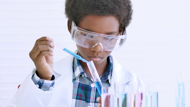 中学生物学实验。用试管前景的男孩在教室里进行科学实验。教育的主题视频下载