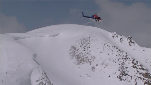 一架救援直升机飞过白雪覆盖的群山。视频下载