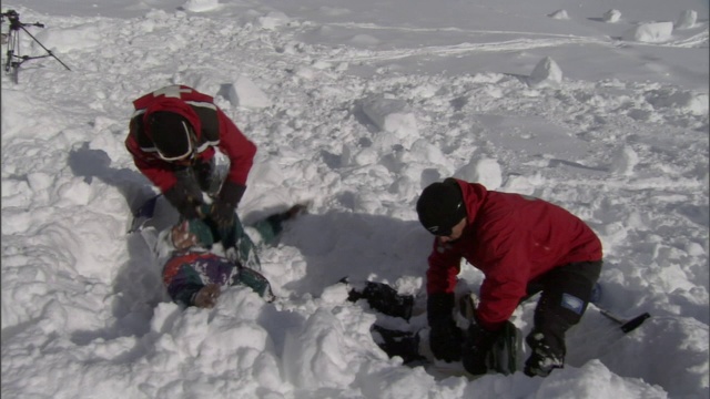 雪崩后，两名救援人员正在挖掘一名被埋在雪中的受害者。视频下载