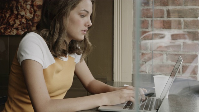 近距离的女孩坐在靠近窗口的笔记本电脑上打字/普罗沃，犹他州，美国视频素材