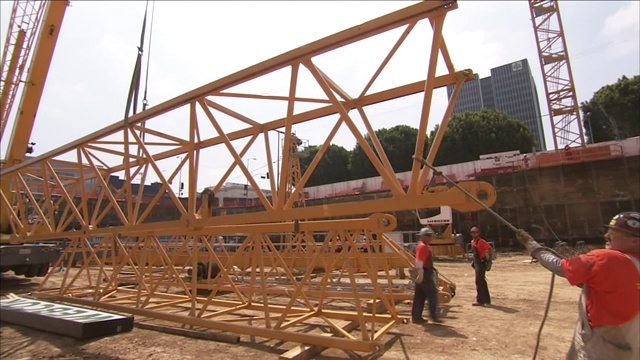建筑工人在起重机的帮助下吊起钢架。视频素材
