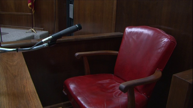 在法庭证人席上，一个麦克风面对着一张红色的椅子。视频素材