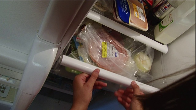 一个女孩从冰箱里取出三明治配料。视频素材