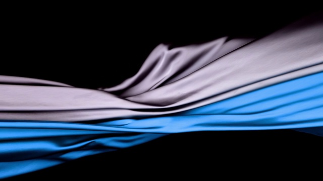 金属银色和蓝色的丝质面料在超慢的动作中横向流动和摆动，近距离，黑色背景视频素材