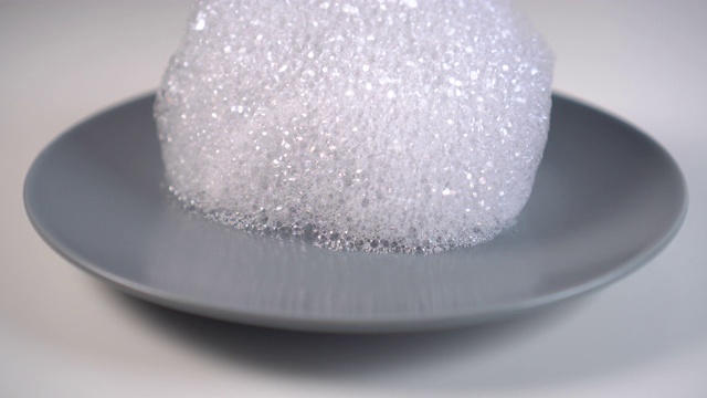 洗涤剂泡沫滴在灰色的陶瓷盘子上视频素材