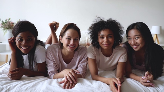 多种族的女性朋友穿着睡衣躺在床上看相机视频素材