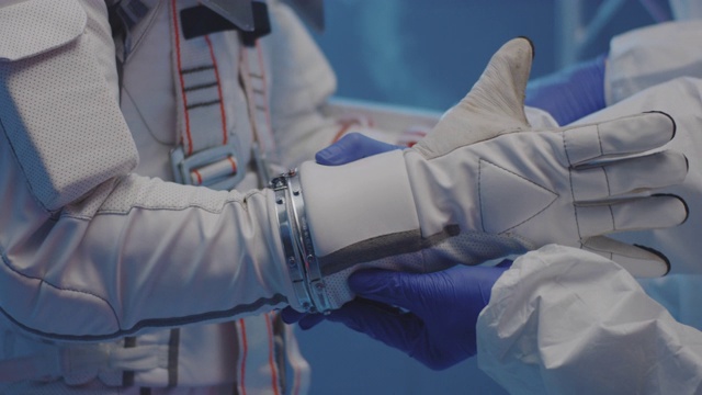 科学家帮助宇航员戴上手套视频素材