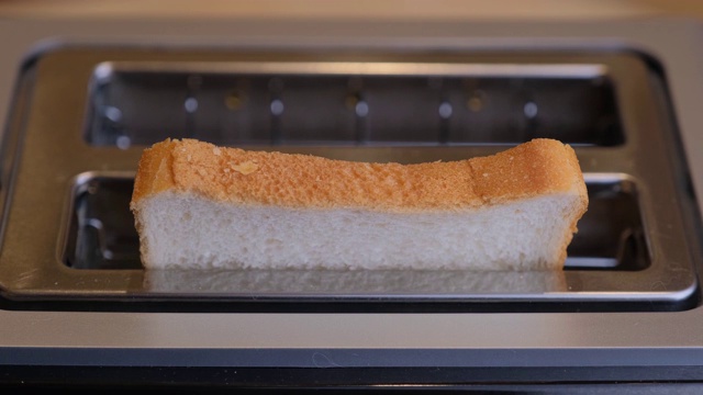 早上烤面包，在家里的厨房里，为早餐准备热烤面包。烤面包。视频下载
