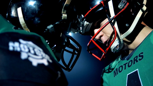 橄榄球运动员用头盔撞头，侧视图。视频下载