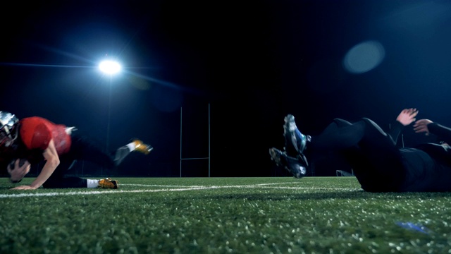 两个美式足球运动员在操场上跑步，踢美式足球，侧视图。视频素材