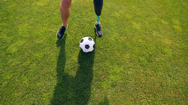 绿油油的草坪上有个残疾人在踢足球，足球视频素材