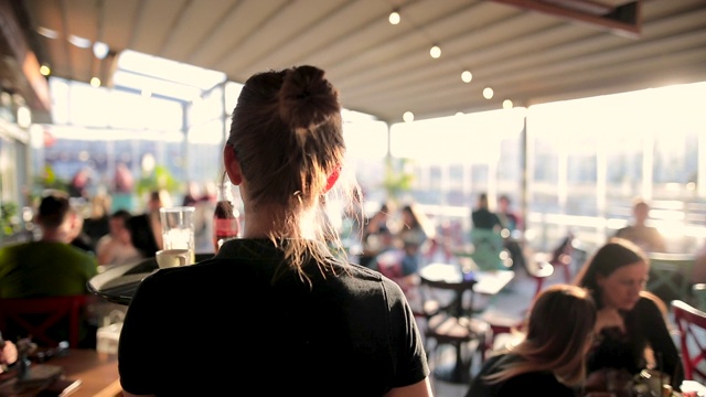 在阳光明媚的日子里，年轻的女服务员在美丽的屋顶咖啡馆提供饮料视频素材
