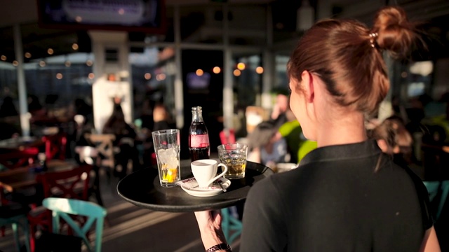 在阳光明媚的日子里，年轻的女服务员在美丽的屋顶咖啡馆提供饮料视频下载