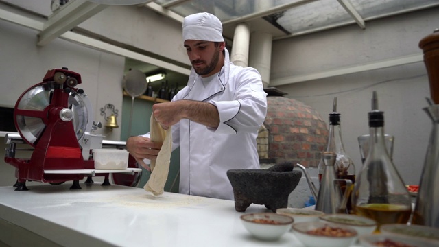 拉丁美洲的年轻厨师在一家意大利餐厅准备披萨视频素材