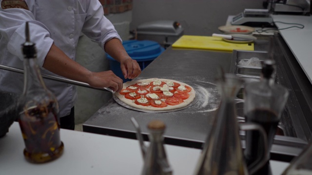 近距离观察一位面目全非的厨师把披萨放到一家餐厅的木制烤箱里视频素材