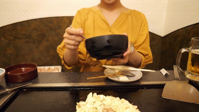 在日式餐厅里，年轻女子在煎锅上做御膳烧视频素材