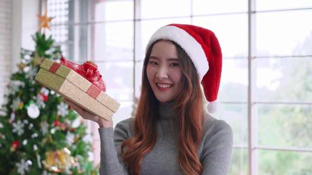 年轻的亚洲女孩拿着圣诞礼物，与微笑的脸视频下载