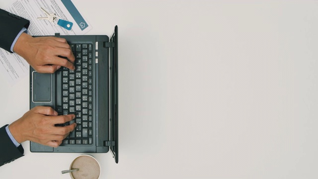 一名房屋销售代理人正在用笔记本电脑工作，在笔记本电脑键盘上敲着合同文件——白色背景的拷贝空间在工作室拍摄视频素材