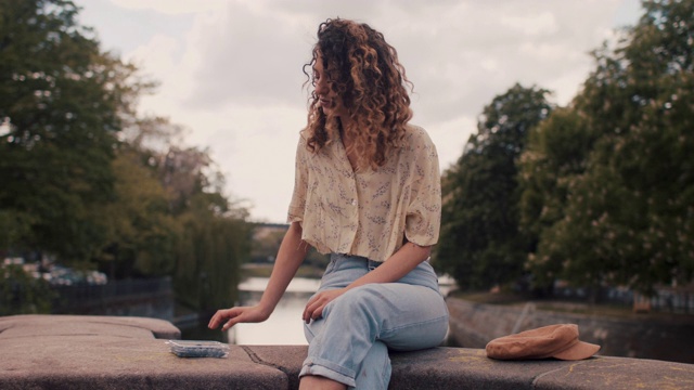 一名年轻女子微笑着坐在柏林施普雷河边的肖像视频素材