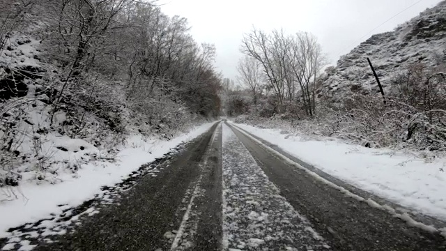 在冰雪覆盖的森林道路上行驶，路面冰冷，路面结冰视频素材