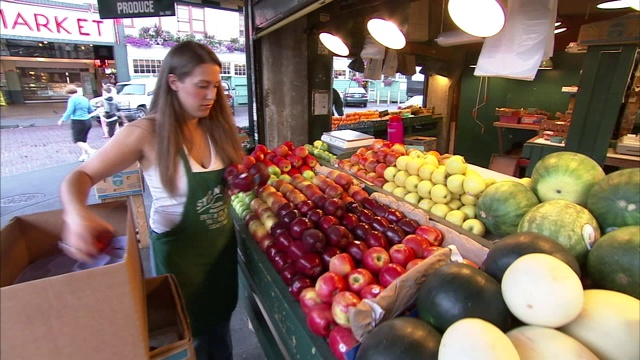 一个小贩在她的农产品摊上装满苹果。视频下载