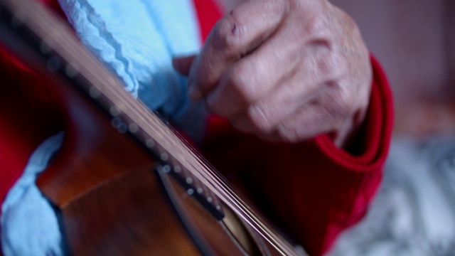 一个老人在弹吉他。音乐和娱乐。一个有皱纹的祖母的肖像，享受音乐和玩得开心。视频素材