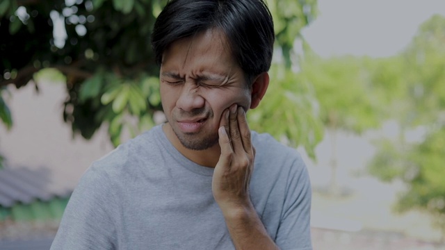 年轻的亚洲男子感到痛苦的不良牙痛，牙齿和牙龈健康问题视频下载