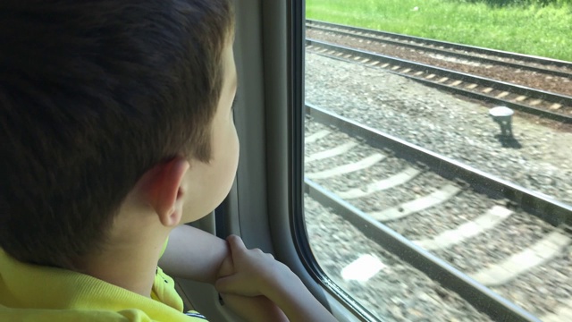 一个十几岁的男孩在行驶的火车上看窗外的风景视频下载