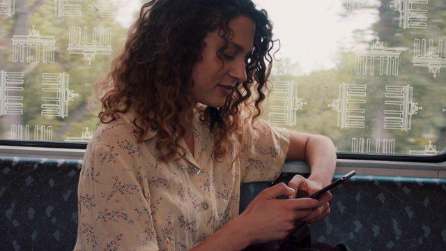 年轻女子坐在火车上，用手机打字，面带微笑视频素材