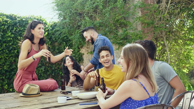 朋友们在户外庭院喝啤酒社交的慢动作视频视频素材